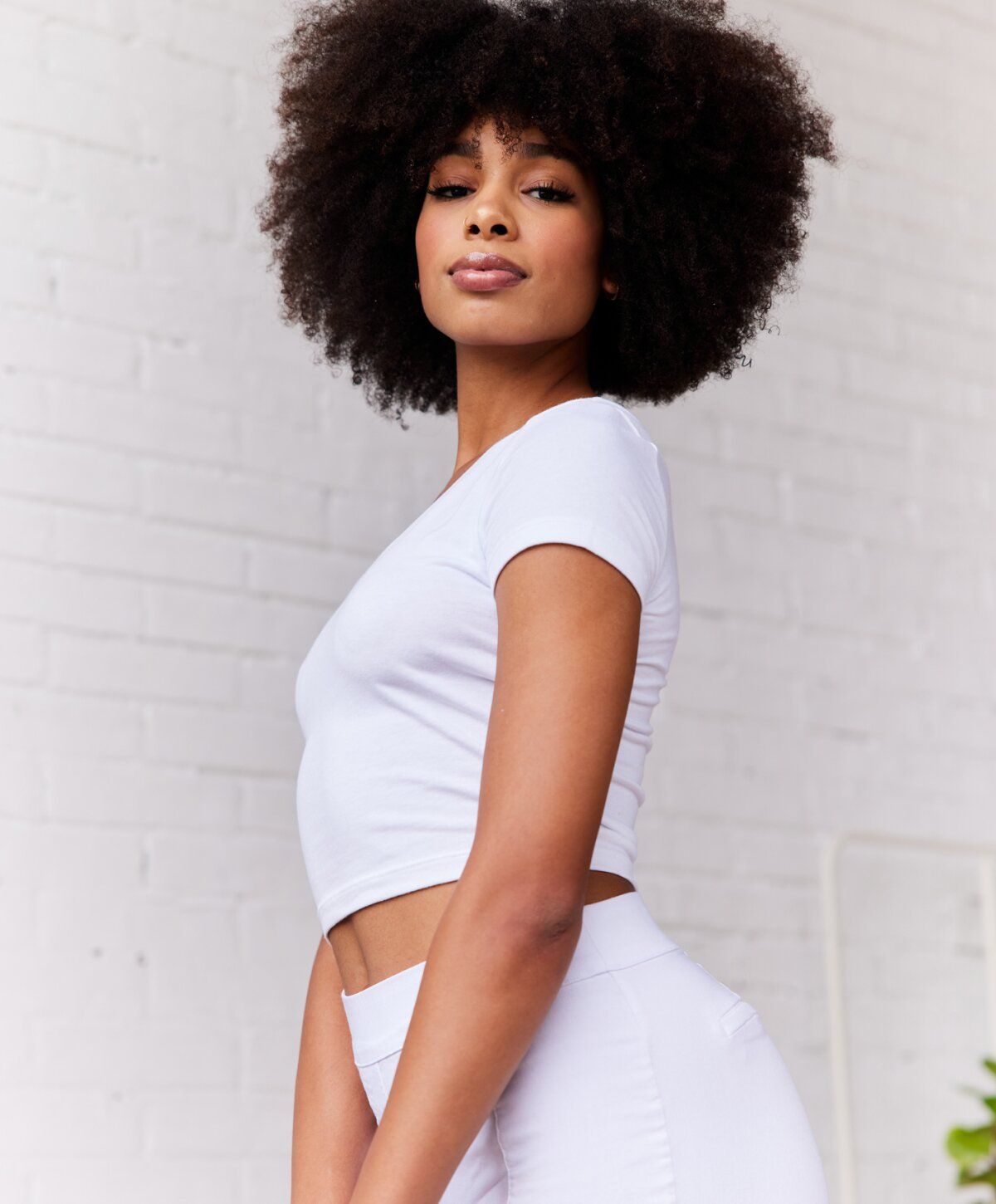 Woman in white outfit with curly hair.