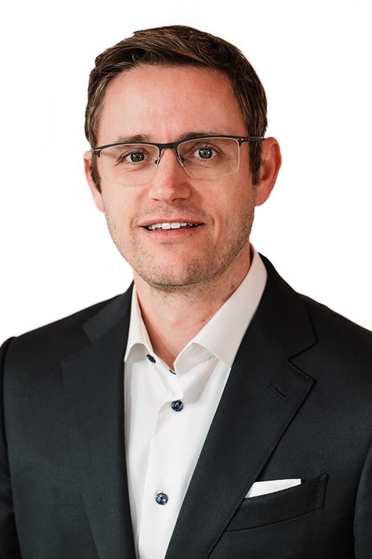Professional man in suit with glasses smiling.