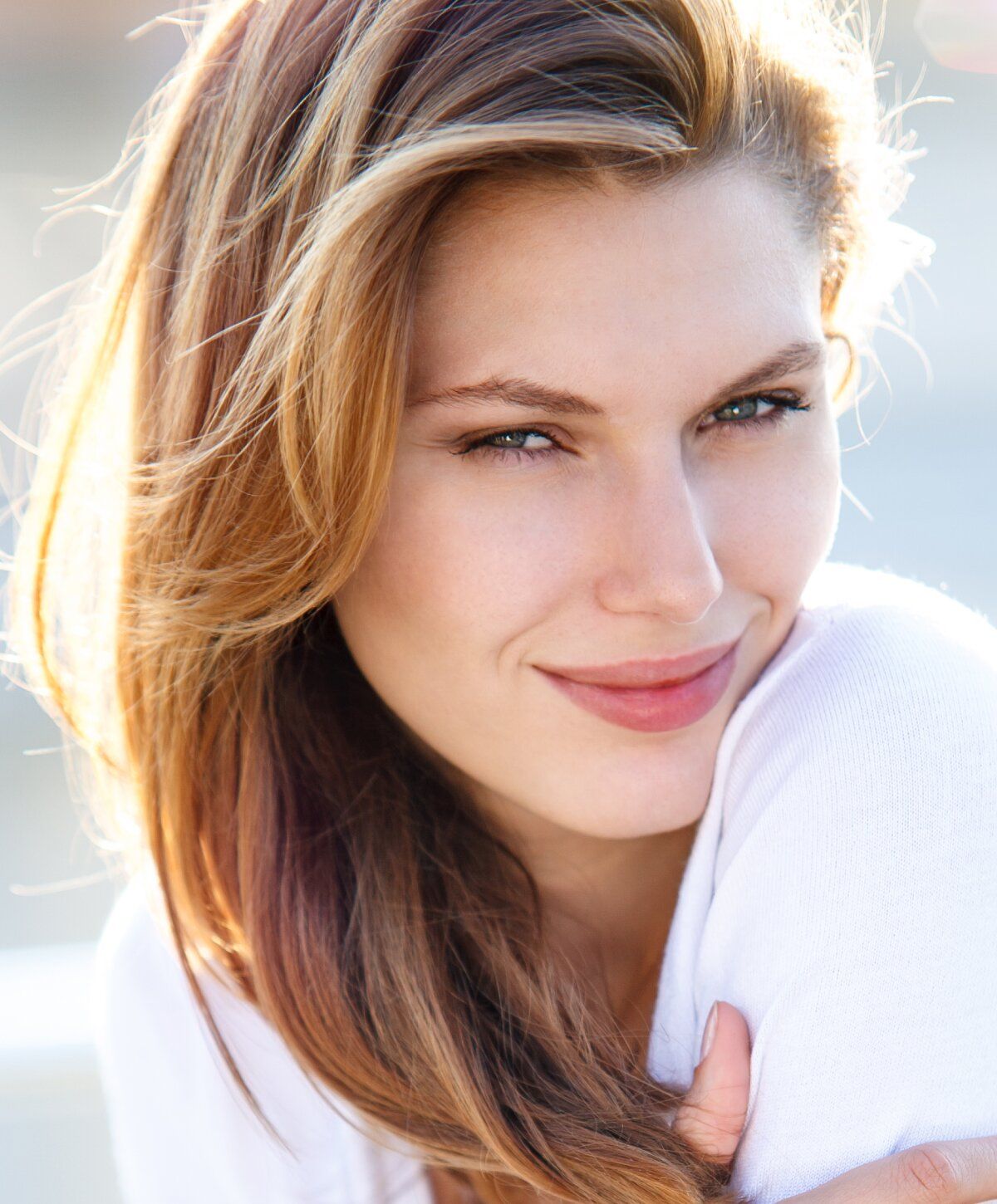 Smiling woman with long, wavy hair outdoors.