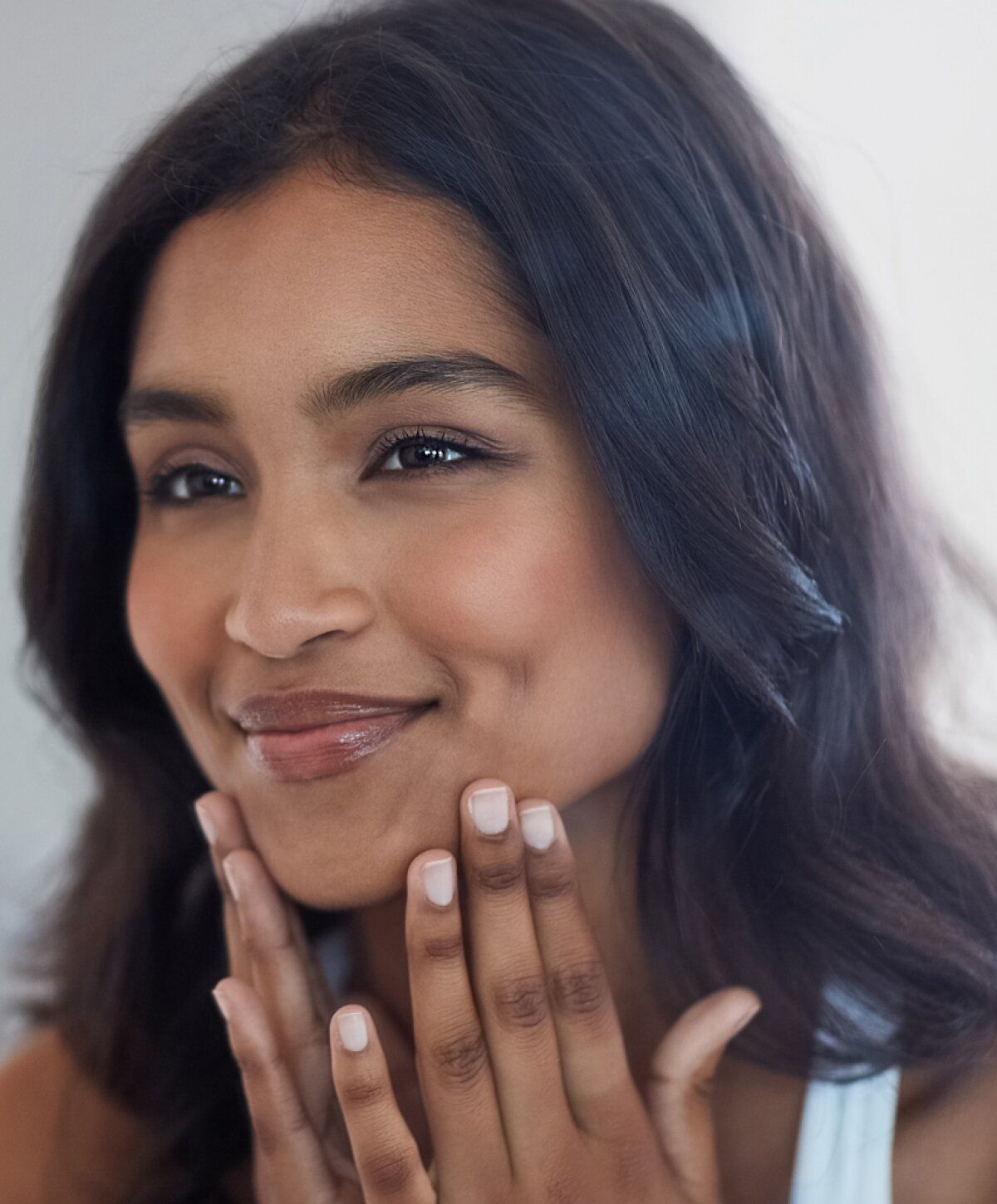Smiling woman touching her face gently.