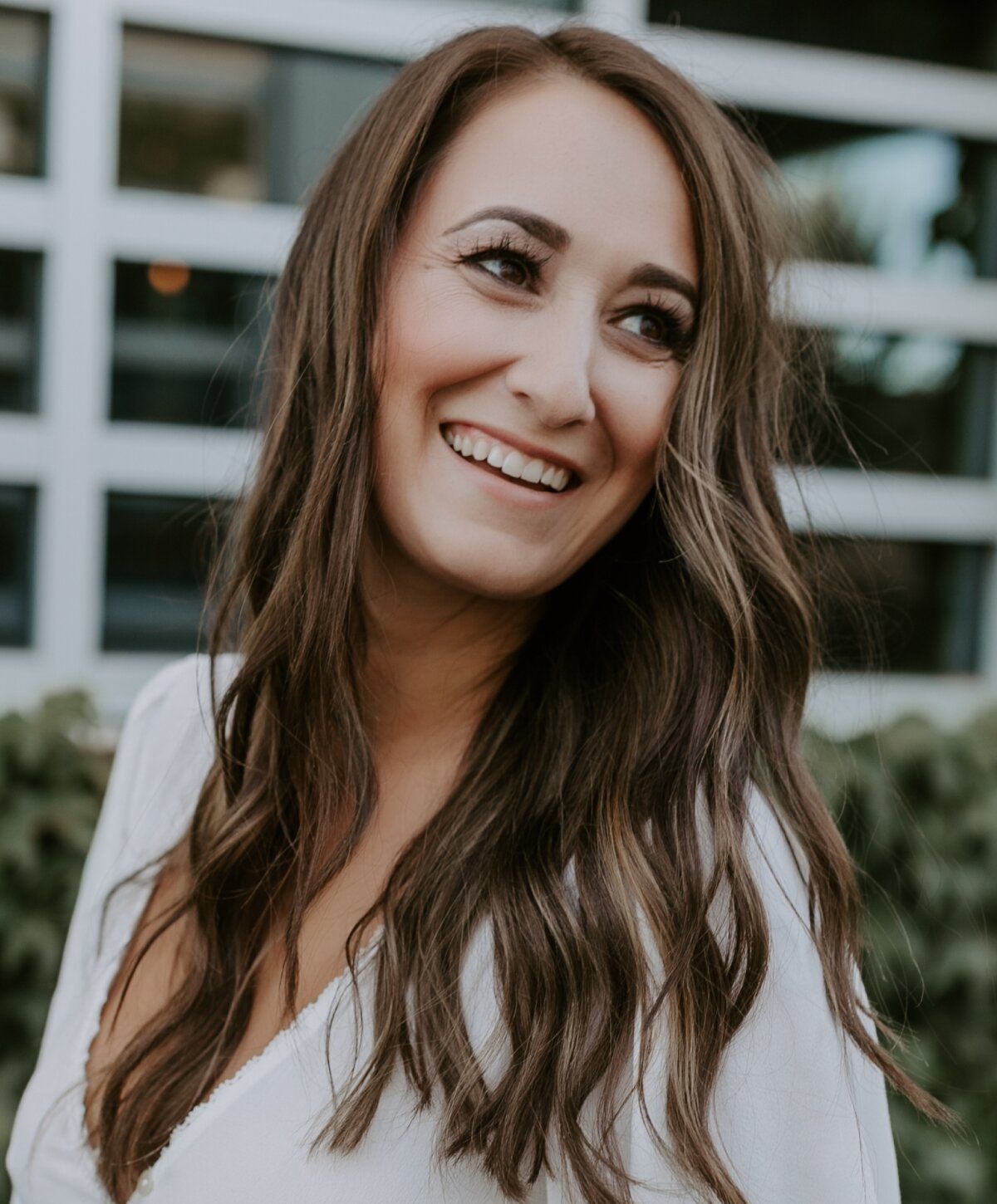 Smiling woman with long wavy hair outdoors.