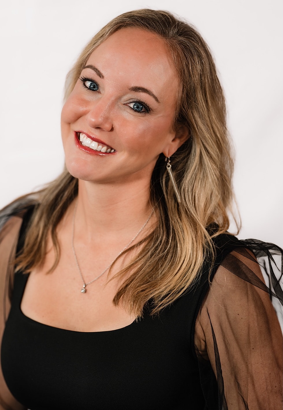 Smiling woman with long hair and black attire.