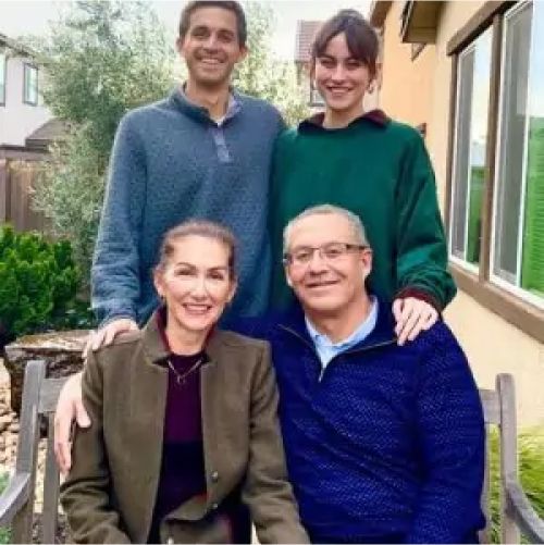 Family portrait outdoors with smiles and sweaters.