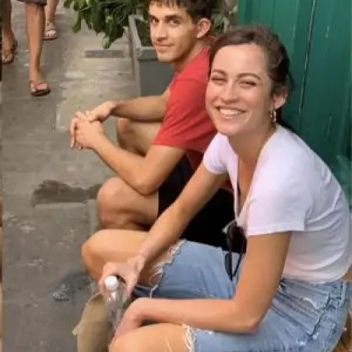 Two friends smiling in a narrow alley.