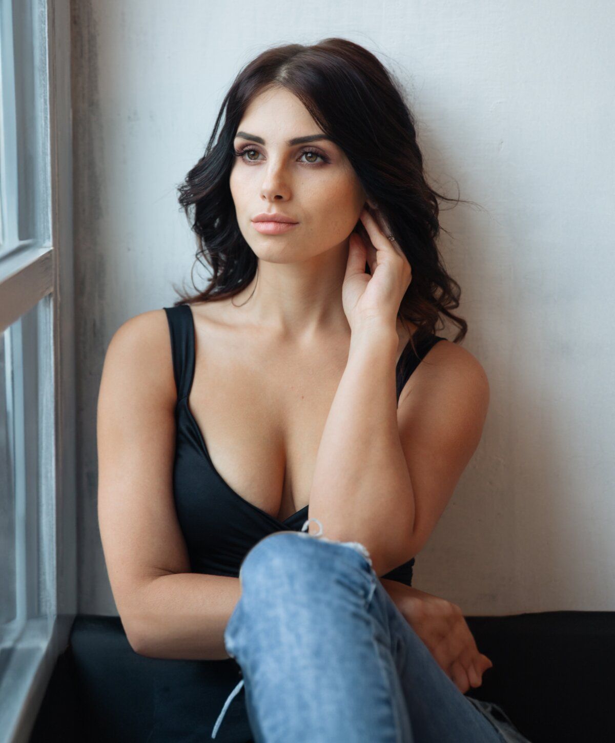 Woman seated by window, thoughtful expression.