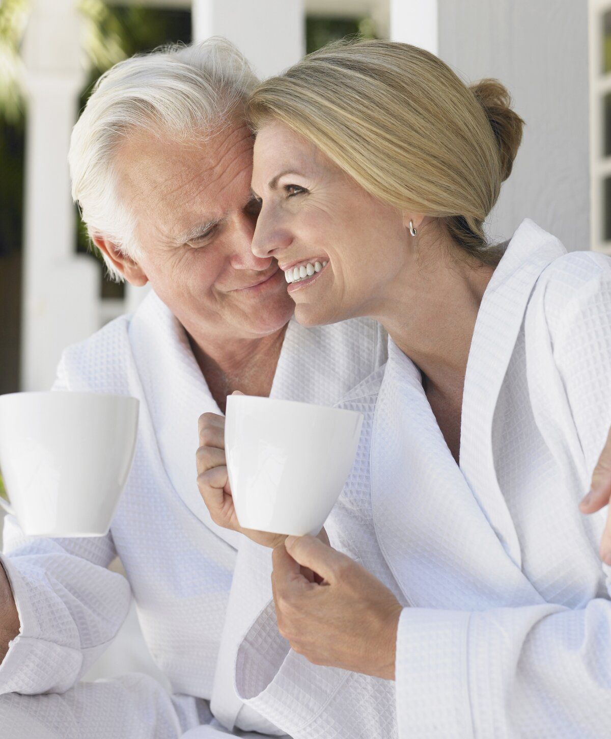 Couple enjoying coffee in cozy bathrobes.