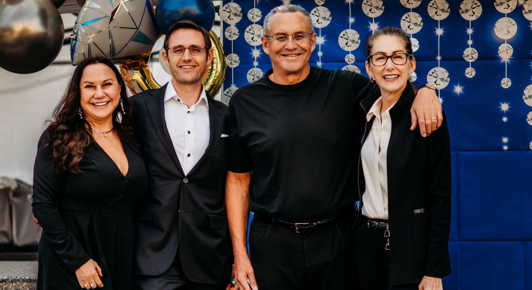 Group photo with balloons and festive backdrop.
