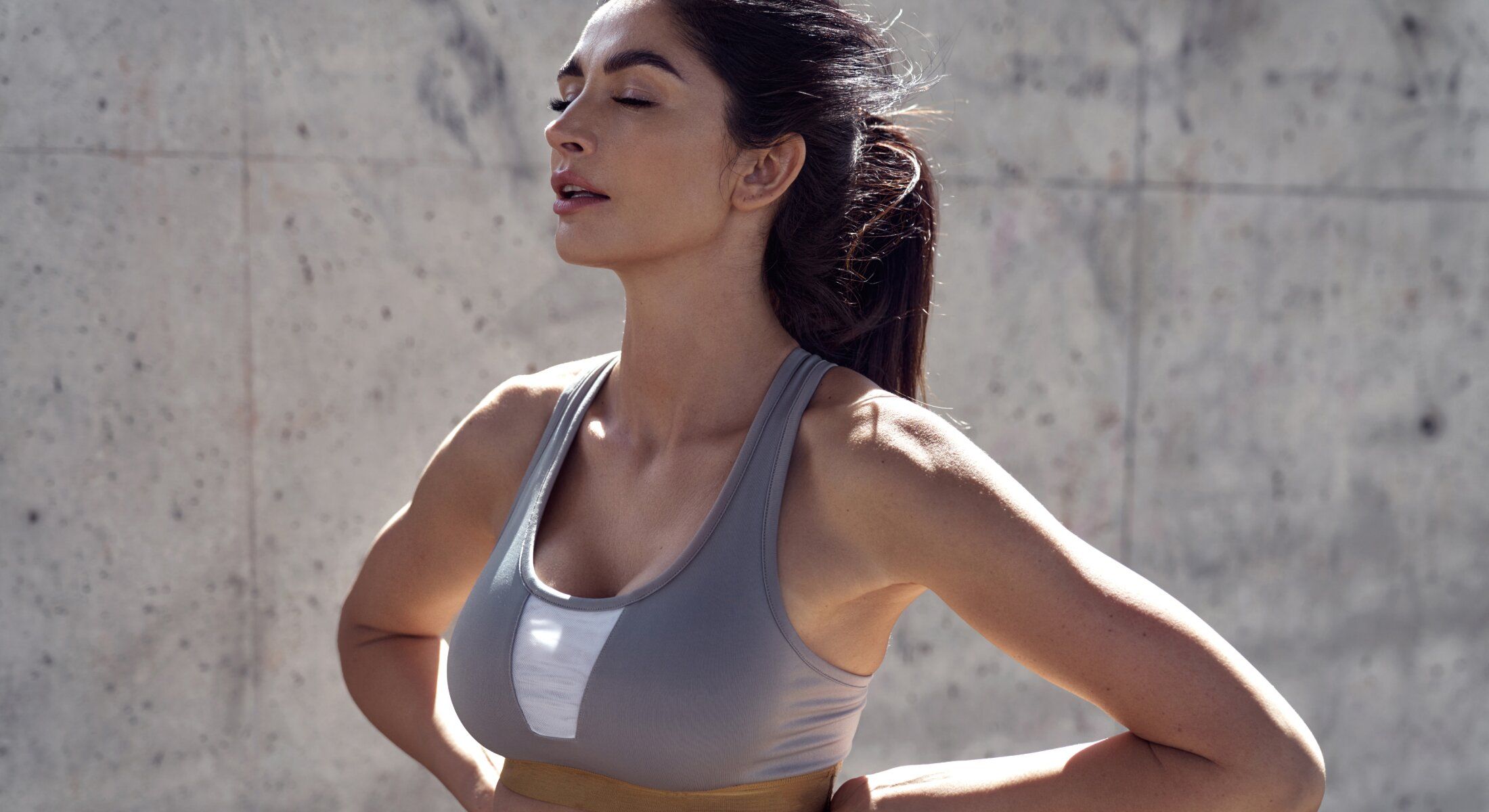 Mujer en ropa deportiva, posando pensativa en el interior.