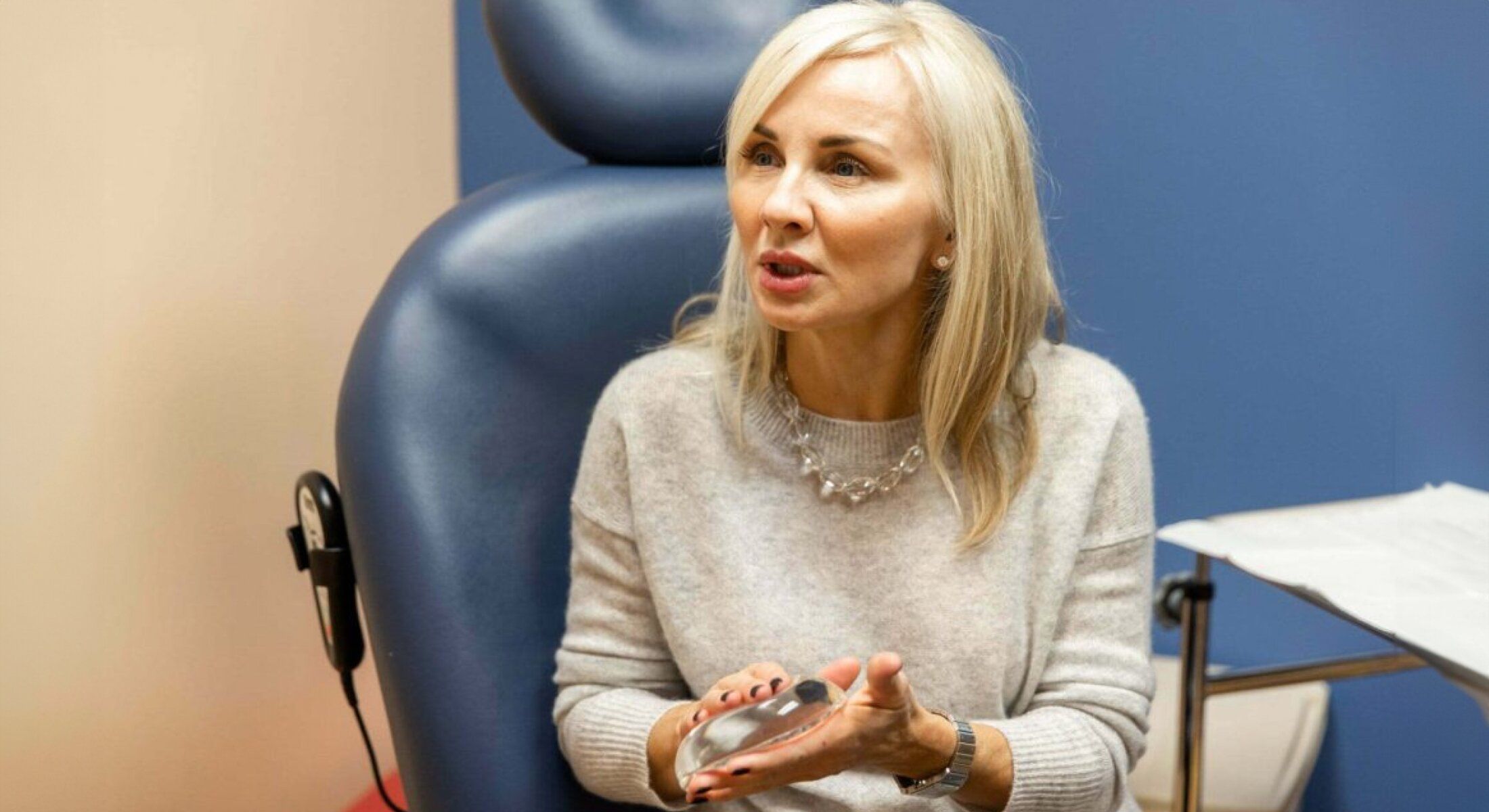 Woman discussing a medical procedure, holding implant.