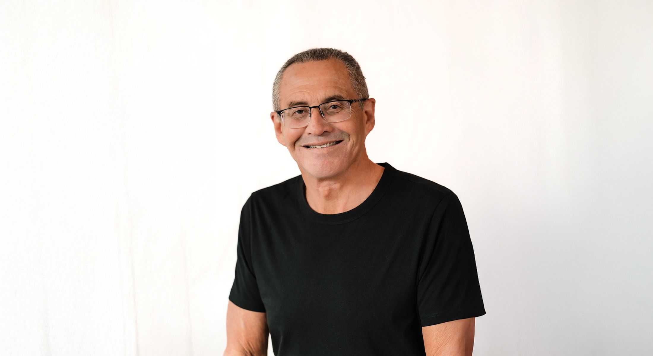Smiling man in black t-shirt against white background.
