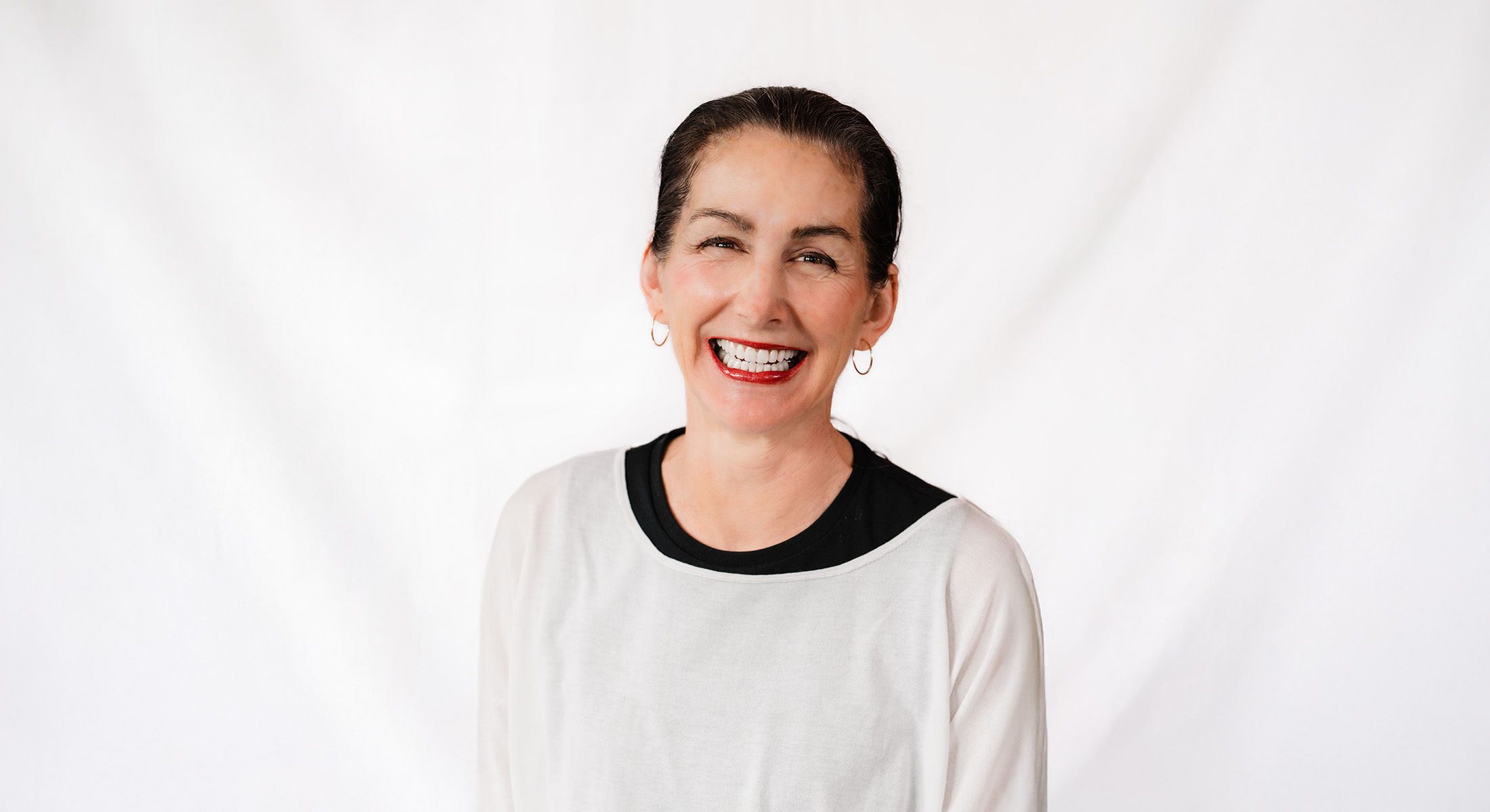 Smiling woman in a casual outfit against white background.