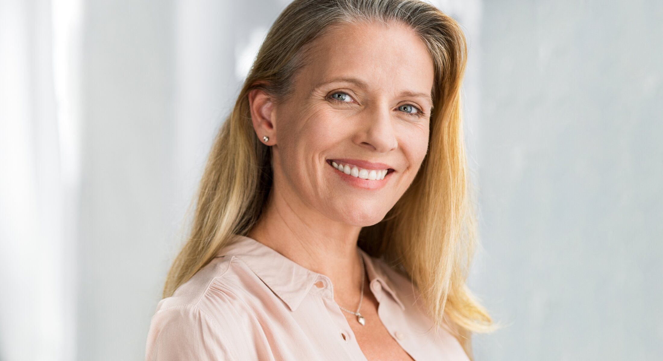 Smiling woman with long blonde hair indoors.